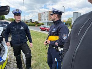 Na zdjęciu widać policjantów stojących koło radiowozu.