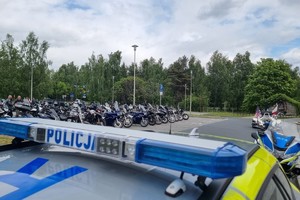 Na zdjęciu widać policyjny radiowóz, motocykl oraz motocykle na przykościelnym parkingu.