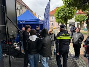 Na zdjęciu widać grupę uczniów i mieszkańców stojących w kolejce do Escape Truck w towarzystwie policjantów.