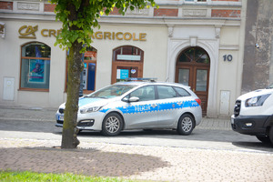 Na zdjęciu widać policyjny radiowóz, a w tle miejskie budynki.
