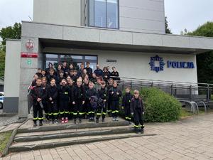 Na zdjęciu widać policjanta oraz uczestników spotkania, na wspólnym zdjęciu przed wejściem do budynku żorskiej komendy.