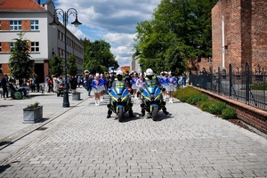 Na zdjęciu widać przemarsz ulicami miasta, a na przodzie kolumny policyjne motocykle.