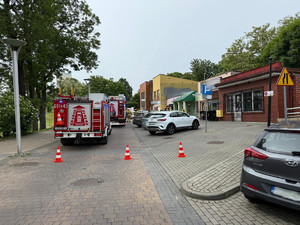 Na zdjęciu widać miejsce zdarzenia drogowego, zaparkowane samochody i pojazdy służb ratunkowych.