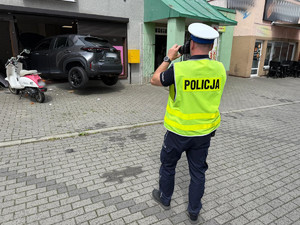 Na zdjęciu widać miejsce zdarzenia drogowego i policjanta, który wykonuje zdjęcia.