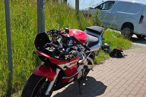 Na zdjęciu widać biały uszkodzony samochód dostawczy oraz czerwony uszkodzony motocykl.