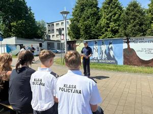 Na zdjęciu widać galerię murali podczas ich tworzenia, a także uczniów i zgromadzonych podczas akcji pod nazwą &quot;Plenerowa lekcja patriotyzmu&quot;.