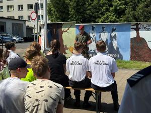 Na zdjęciu widać galerię murali podczas ich tworzenia, a także uczniów i zgromadzonych podczas akcji pod nazwą &quot;Plenerowa lekcja patriotyzmu&quot;.