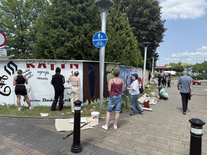 Na zdjęciu widać galerię murali podczas ich tworzenia, a także uczniów i zgromadzonych podczas akcji pod nazwą &quot;Plenerowa lekcja patriotyzmu&quot;.