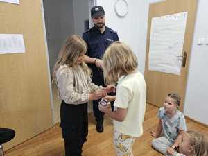 Na zdjęciu widać policjanta oraz uczestników półkolonii podczas wspólnych zajęć.