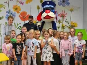 Na zdjęciu widać policjanta, uczestniczących w spotkaniu pierwszoklasistów i Sznupka.