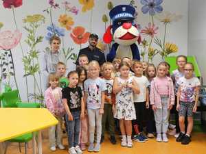 Na zdjęciu widać policjanta, uczestniczących w spotkaniu pierwszoklasistów i Sznupka.