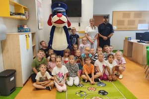 Na zdjęciu widać uczniów w sali lekcyjnej, policjanta oraz Sznupka.