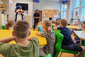 Na zdjęciu widać uczniów w sali lekcyjnej, policjanta oraz Sznupka.