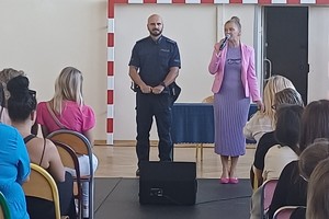 Na zdjęciu widać rodziców uczniów zgromadzonych w sali oraz policjanta i przedstawiciela szkoły.