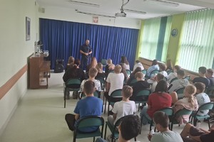 Na zdjęciu widać uczniów i policjanta podczas spotkania profilaktycznego.