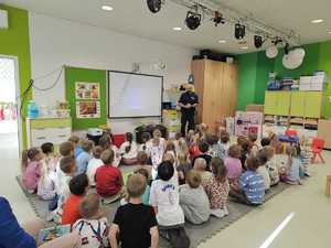 Na zdjęciu widać policjanta i zgromadzone przed nim dzieci.