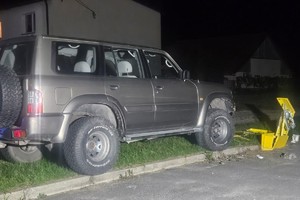 Na zdjęciu widać szary samochód typu terenowego, a także uszkodzoną skrzynkę gazową oraz sąsiadujące zabudowania.
