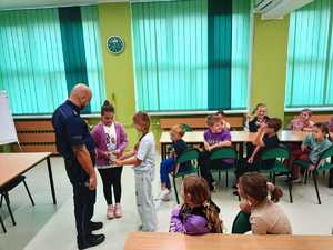 Na zdjęciu widać policjanta oraz dzieci podczas spotkania.