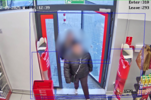 Na zdjęciu widać wejście do sklepu i rozmazane osoby, które wchodzą do sklepu.