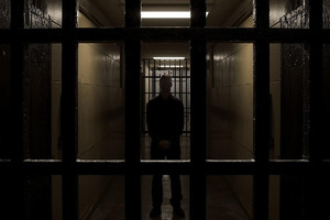 Grafika przedstawia mężczyznę za kratami.