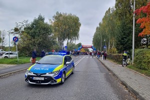 Na zdjęciu widać radiowóz, a w tle uczestników biegu.