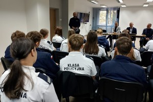 Na zdjęciu widać policjanta, prelegentów oraz uczestników debaty w zgromadzonych w sali odpraw żorskiej komendy Policji.