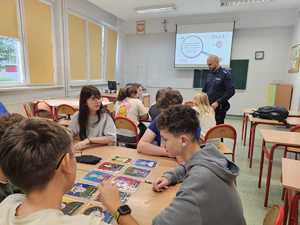Na zdjęciu widać policjanta oraz uczniów w sali lekcyjnej podczas przeprowadzanych zajęć.