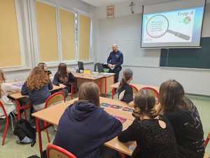 Na zdjęciu widać policjanta oraz uczniów w sali lekcyjnej podczas przeprowadzanych zajęć.