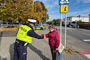 Na zdjęciu widać policjanta w rejonie przejścia dla pieszych oraz osobę otrzymującą odblask.