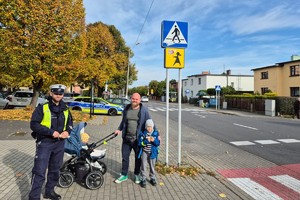 Na zdjęciu widać policjanta w rejonie przejścia dla pieszych oraz osobę otrzymującą odblask.