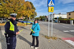 Na zdjęciu widać policjanta w rejonie przejścia dla pieszych oraz osobę otrzymującą odblask.