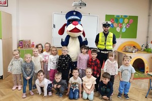 Na zdjęciu widać policjanta, Sznupka oraz przedszkolaków na wspólnym zdjęciu.