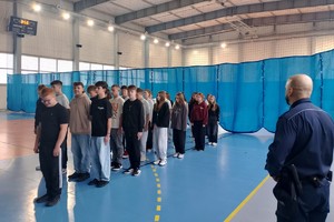 Na zdjęciu widać policjanta oraz uczniów podczas zajęć musztry.