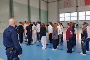 Na zdjęciu widać policjanta oraz uczniów podczas zajęć musztry.