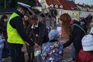Na zdjęciu widać policjanta oraz kobietę i dzieci.