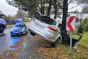 Na zdjęciu widać uszkodzony srebrny samochód, miejsce zdarzenia drogowego, radiowóz.