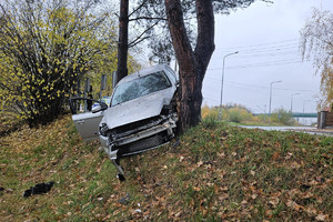 Na zdjęciu widać uszkodzony srebrny samochód, miejsce zdarzenia drogowego, radiowóz.