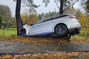Na zdjęciu widać uszkodzony srebrny samochód, miejsce zdarzenia drogowego, radiowóz.