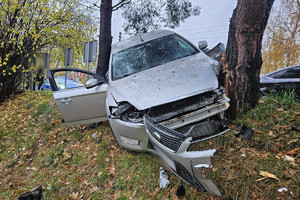 Na zdjęciu widać uszkodzony srebrny samochód, miejsce zdarzenia drogowego, radiowóz.