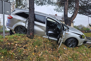 Na zdjęciu widać uszkodzony srebrny samochód, miejsce zdarzenia drogowego, radiowóz.