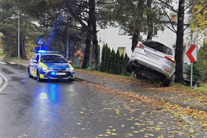 Na zdjęciu widać uszkodzony srebrny samochód, miejsce zdarzenia drogowego, radiowóz.