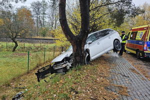 Na zdjęciu widać uszkodzony srebrny samochód, miejsce zdarzenia drogowego, radiowóz.