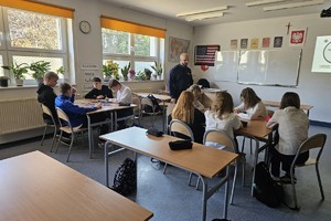 Na zdjęciu widać policjanta oraz uczniów w czasie zajęć w sali lekcyjnej.