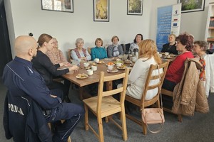 Na zdjęciu widać policjanta oraz osoby zgromadzone podczas spotkania.