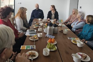Na zdjęciu widać policjanta oraz osoby zgromadzone podczas spotkania.