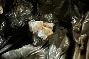 Na zdjęciu widać czarny worek z pieniędzmi w środku.