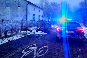 Na zdjęciu widać radiowóz, ciąg pieszo-rowerowy, rower oraz zabudowania.