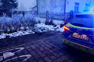 Na zdjęciu widać radiowóz, ciąg pieszo-rowerowy, rower oraz zabudowania.