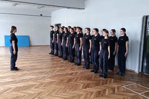 Na zdjęciu widać policjanta i uczniów podczas zajęć z musztry.