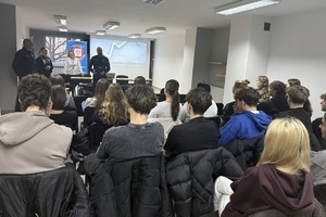 Na zdjęciu widać policjantów, przedstawicielkę sanepidu oraz zgromadzonych uczniów.